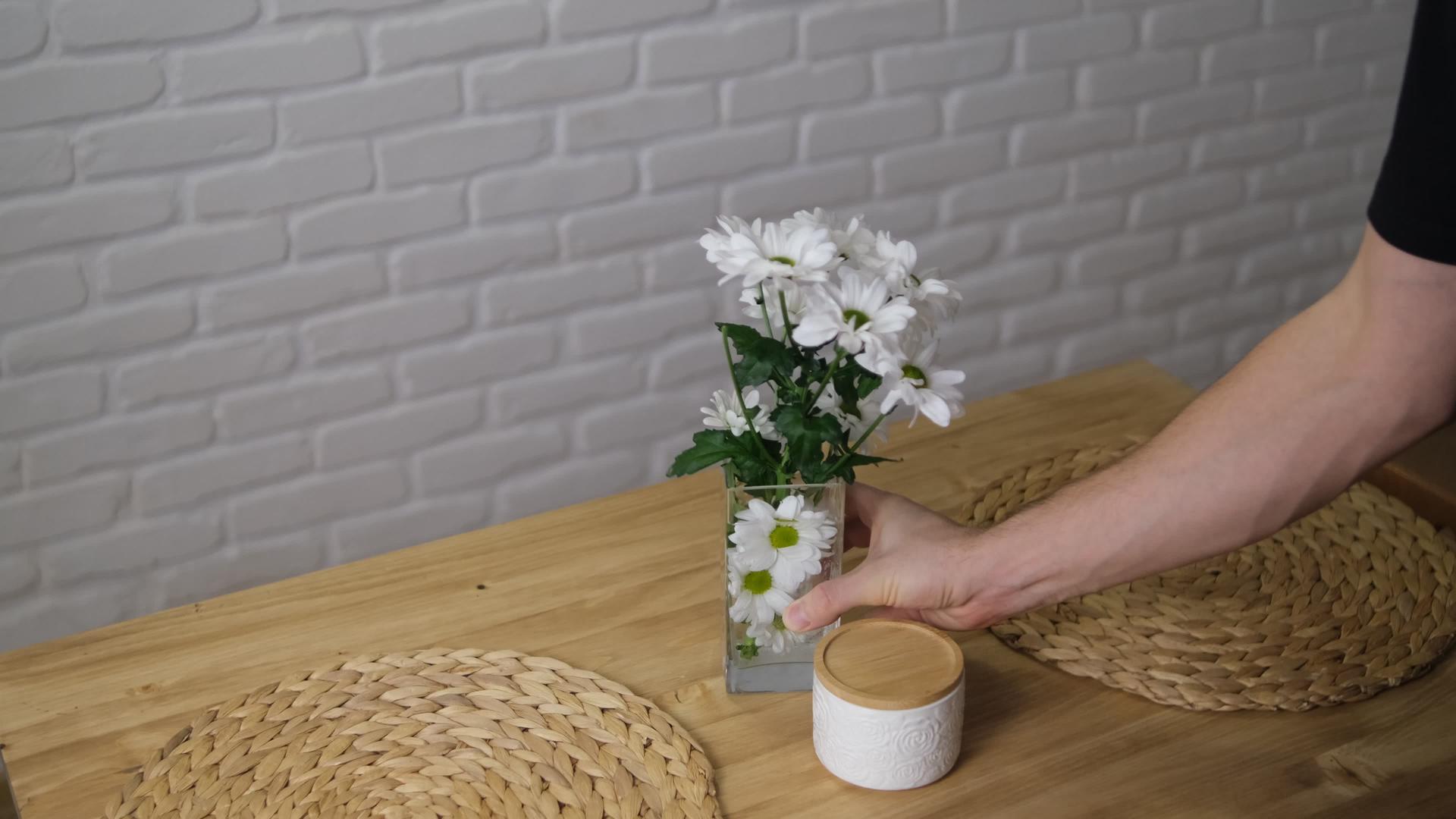 花瓶里的花被放在桌子上用来装饰家里的花、木桌和砖墙视频的预览图
