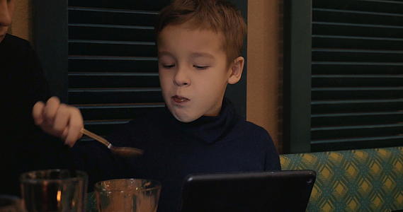 男孩们在咖啡馆吃冰淇淋看平板电脑视频的预览图