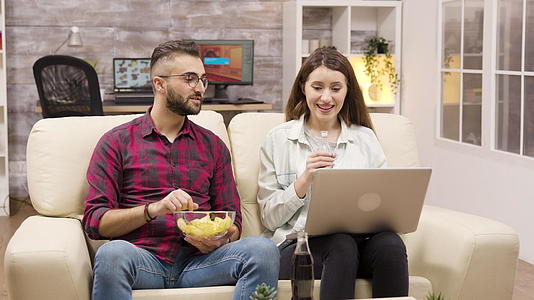 快乐的夫妇在沙发上吃薯片视频的预览图