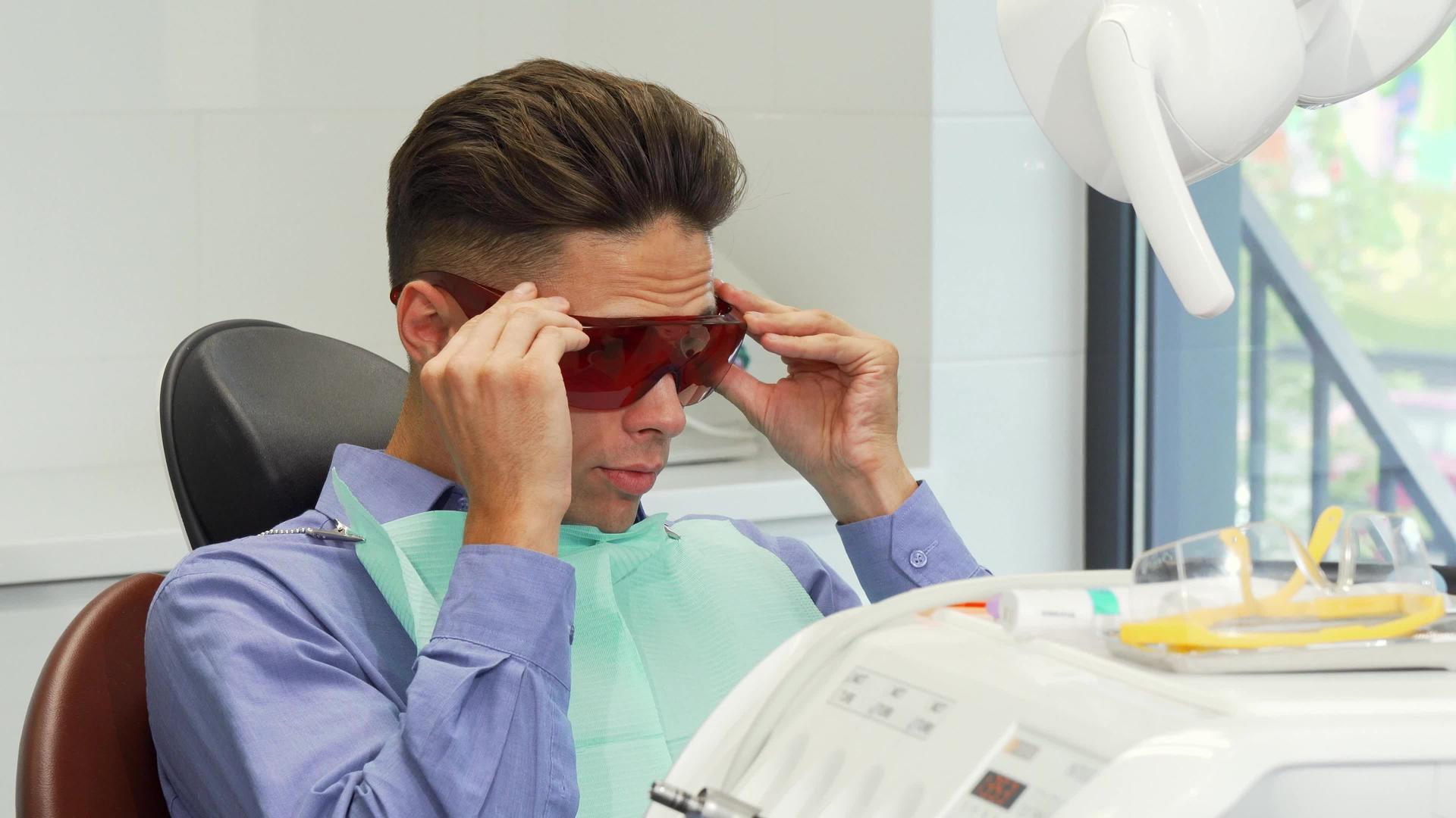 男性患者戴着保护眼镜在牙医办公室露出拇指视频的预览图