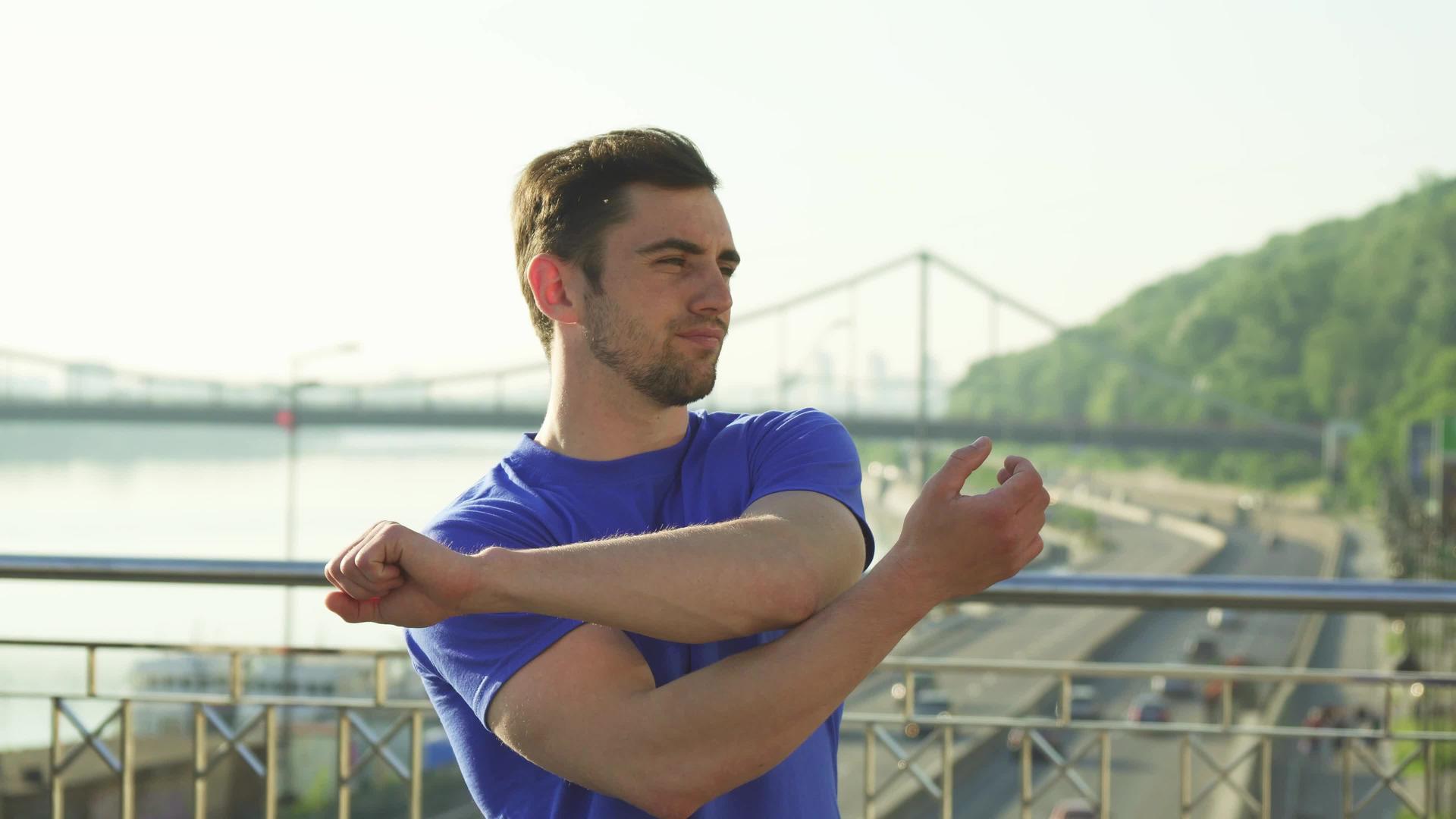 帅帅的运动员在健身前在户外伸展双臂视频的预览图
