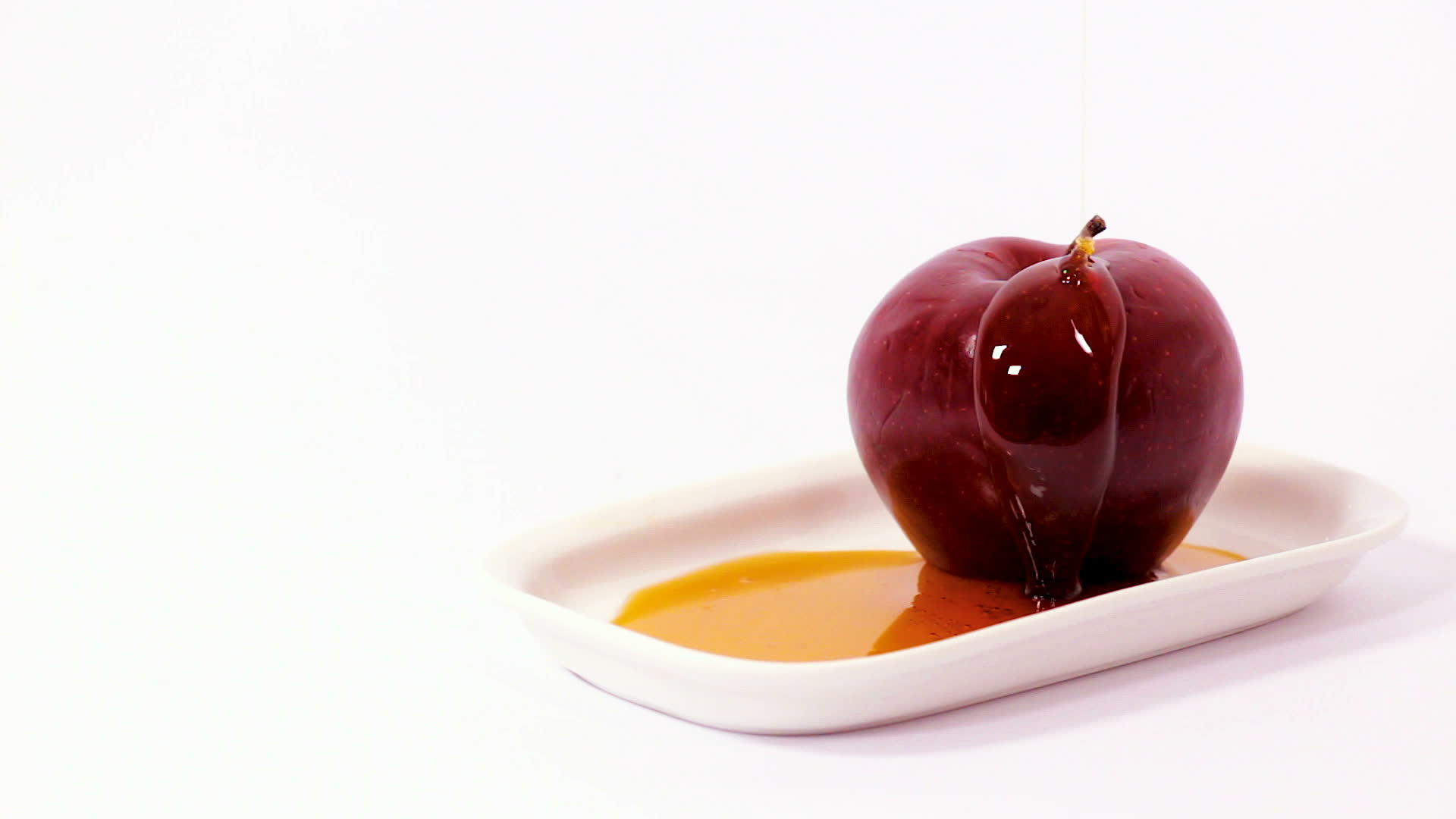 把蜂蜜倒在白色的盘子上红苹果上的电影视频的预览图