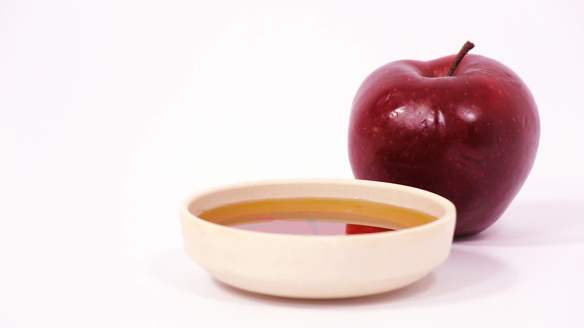 红苹果和一碗蜂蜜在白色背景下视频的预览图