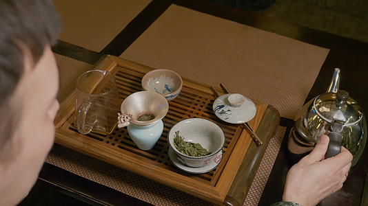 茶主把热水从酒壶里倒到木桌上加入绿茶视频的预览图