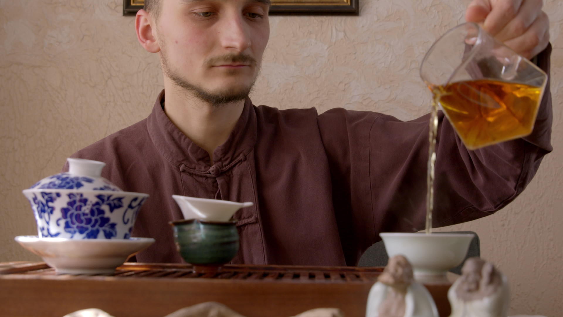 茶大师把新鲜的饮料从公平的投手倒进碗里的木托盘里视频的预览图