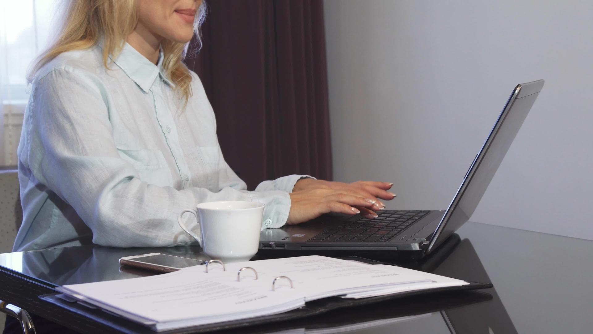 一名妇女在文件夹中阅读重要文件然后将其输入笔记本电脑视频的预览图