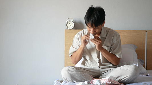 穿着睡衣的亚洲男子因过敏而打喷嚏视频的预览图