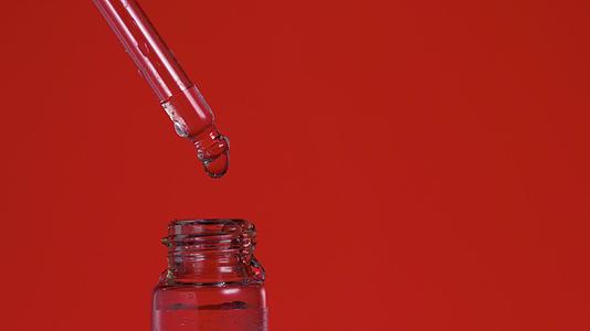 有机精油的液体油落在红底玻璃瓶里视频的预览图
