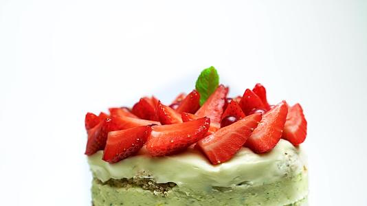 美味的蛋糕覆盖着草莓和薄荷蔓越莓在白色背景下装饰着视频的预览图