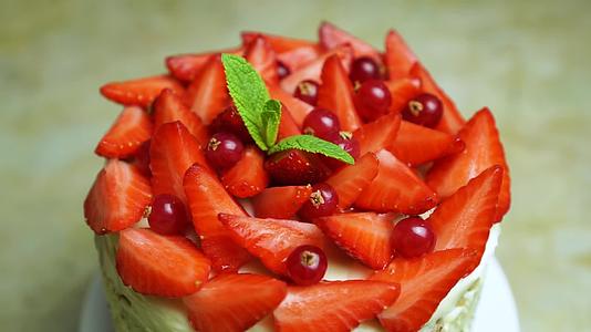 桌面拍摄旋转草莓和薄荷用小红莓装饰美味蛋糕夏天很甜视频的预览图