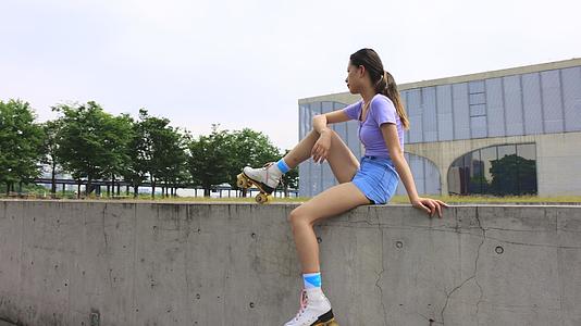 运动女孩穿着轮滑鞋坐着休息视频的预览图