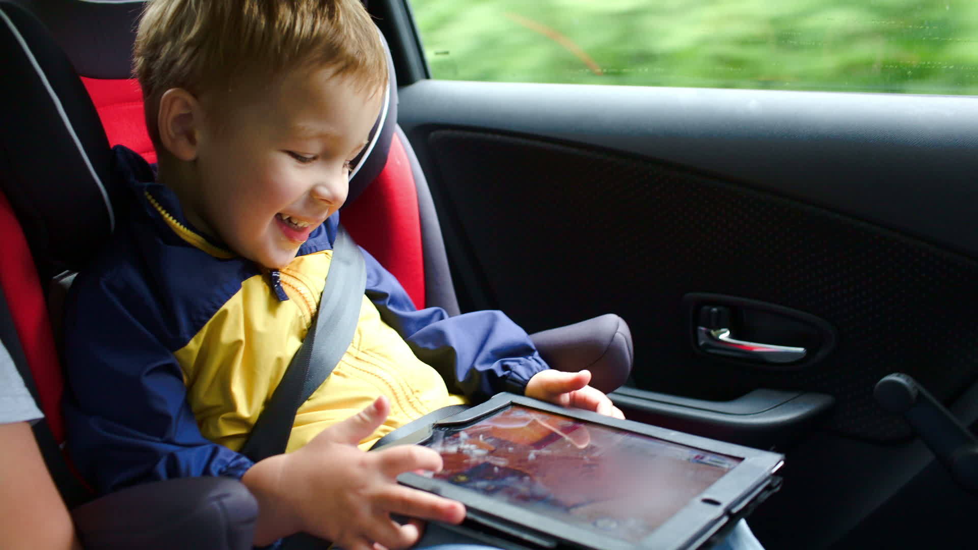 小男孩在车里玩平板电脑游戏视频的预览图