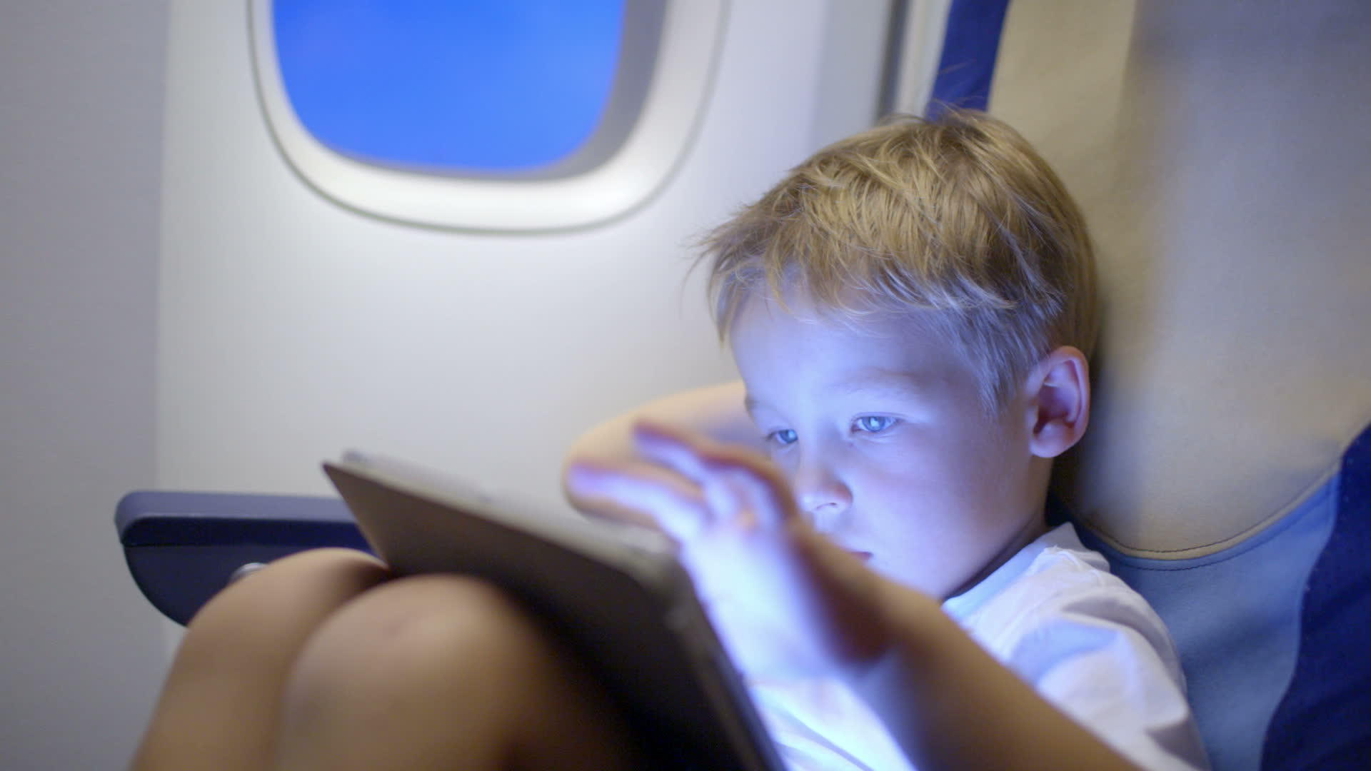 在飞机上用平板电脑玩得无聊或疲惫的男孩视频的预览图
