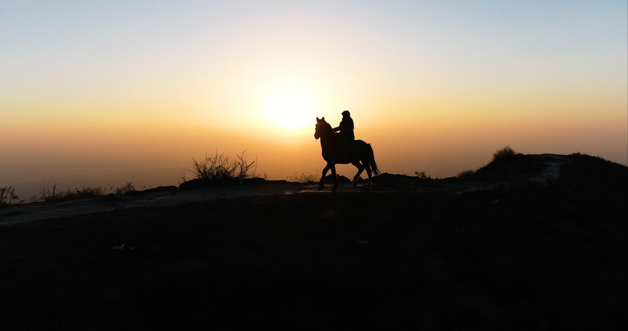 日出山顶骑马镜头剪影航拍视频的预览图
