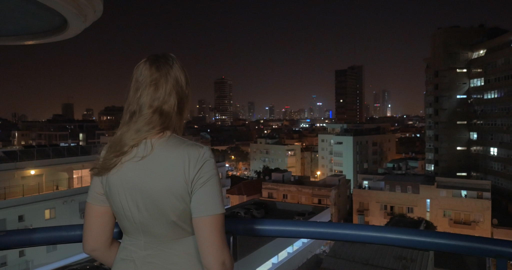 女人从屋顶欣赏夜城的风景视频的预览图