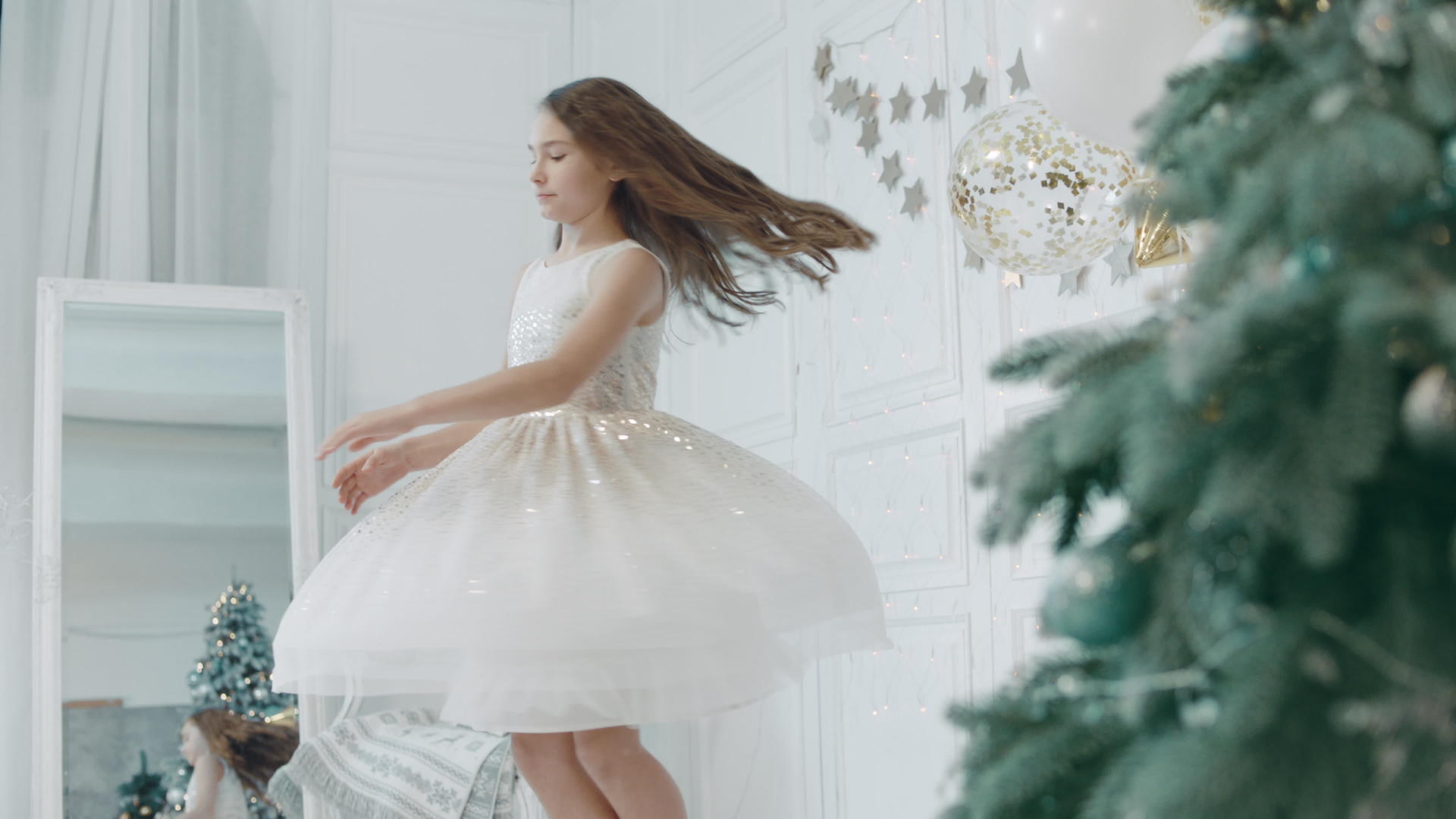 美丽的女孩在圣诞树附近旋转穿白裙的视频的预览图
