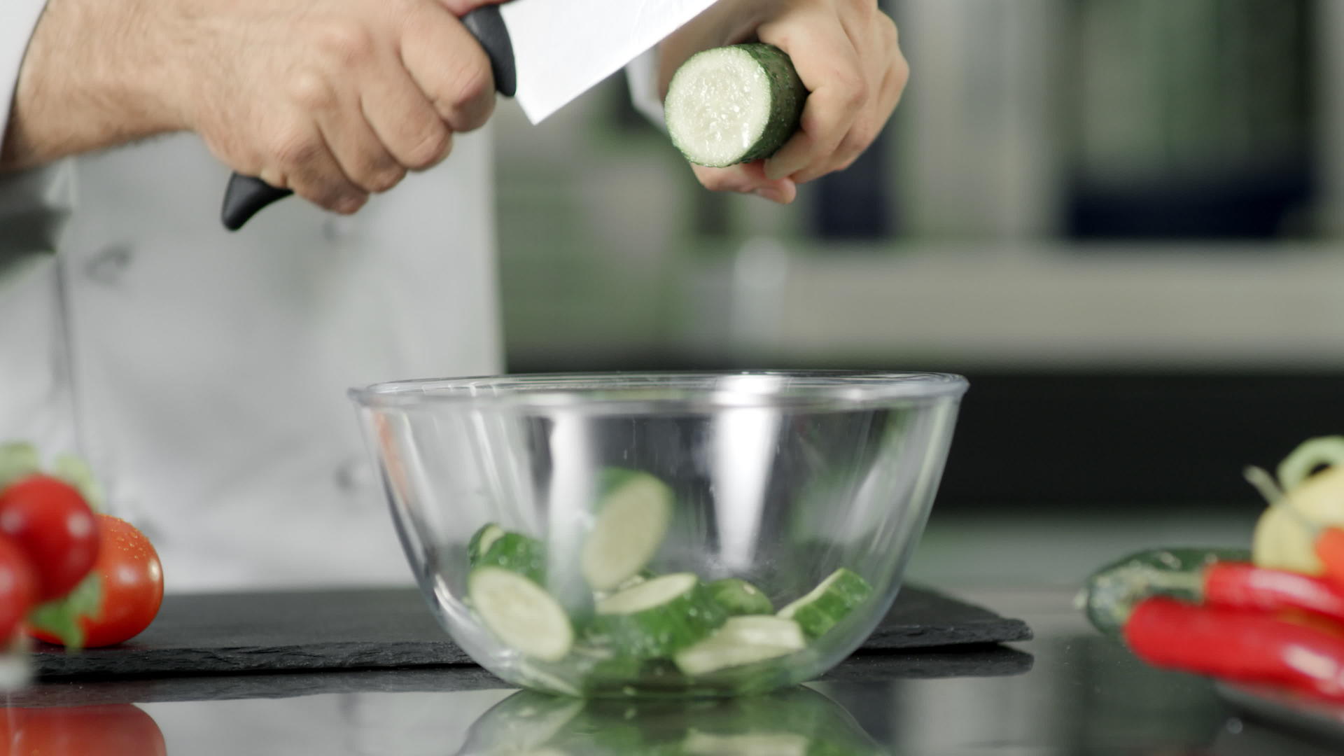厨师在玻璃碗里慢慢地在厨房里切新鲜黄瓜视频的预览图