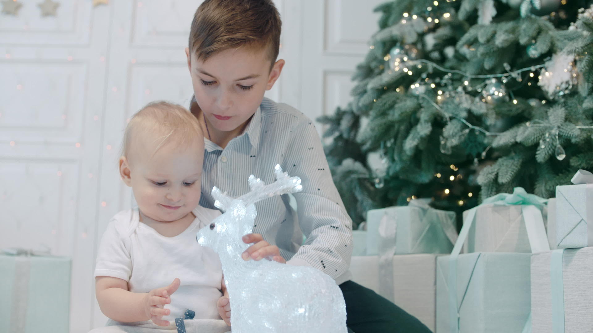 两个可爱的兄弟姐妹坐在圣诞树下拆除礼物视频的预览图