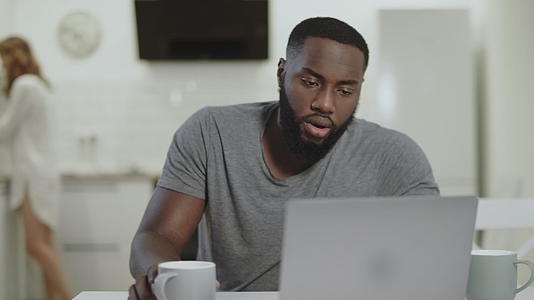 集中的黑人男子在露天厨房做笔记本电脑视频的预览图