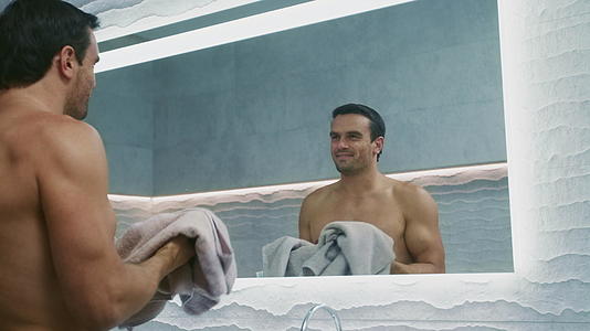 在浴室里用毛巾擦脸的快乐男人视频的预览图