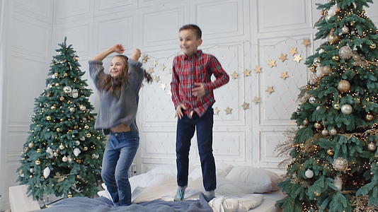 在卧室的两棵圣诞树下孩子们在床上跳跃视频的预览图