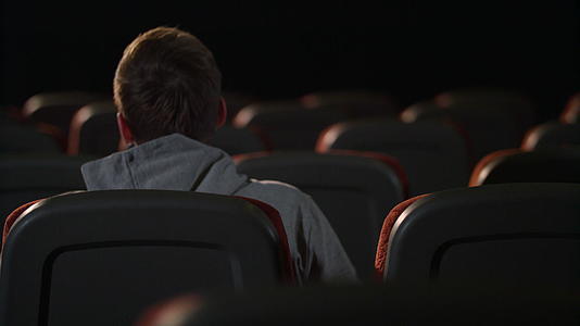 一个男人坐在空荡荡的电影院里视频的预览图