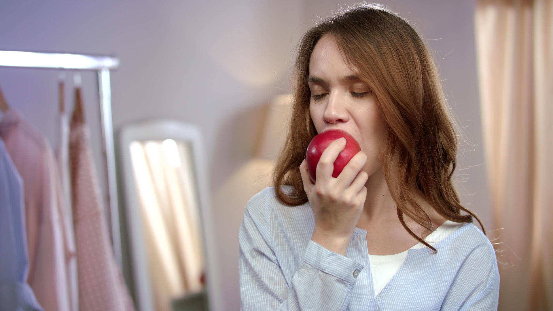快乐女人在家吃红苹果的肖像视频的预览图