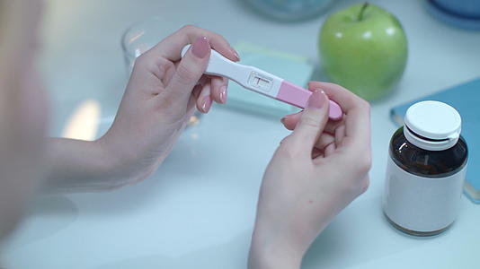 女性手中的阳性妊娠测试棒视频的预览图
