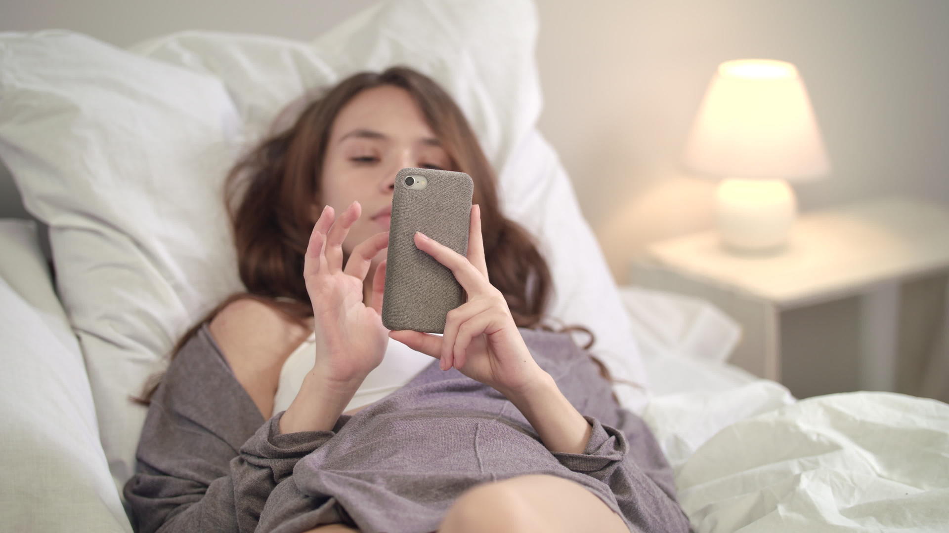 在床上使用移动电话放松女性视频的预览图