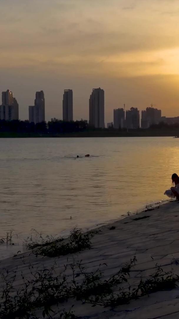 夕阳下江边亲子玩水的人群素材视频的预览图