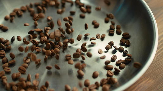 烤咖啡豆慢慢地落在金属碗的表面视频的预览图