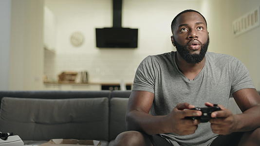 在家里厨房玩电子游戏的笑黑人男人视频的预览图