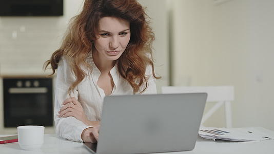 微笑的女人在笔记本电脑上读快乐的新闻视频的预览图