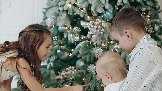 客厅里的圣诞树周围有三个可爱的孩子视频的预览图