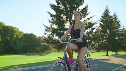在夏天的公园里骑自行车时疲惫的女人和女人从脸上擦汗视频的预览图