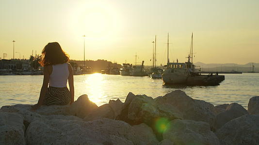 黄昏时分女孩在海港的石头上旅行视频的预览图