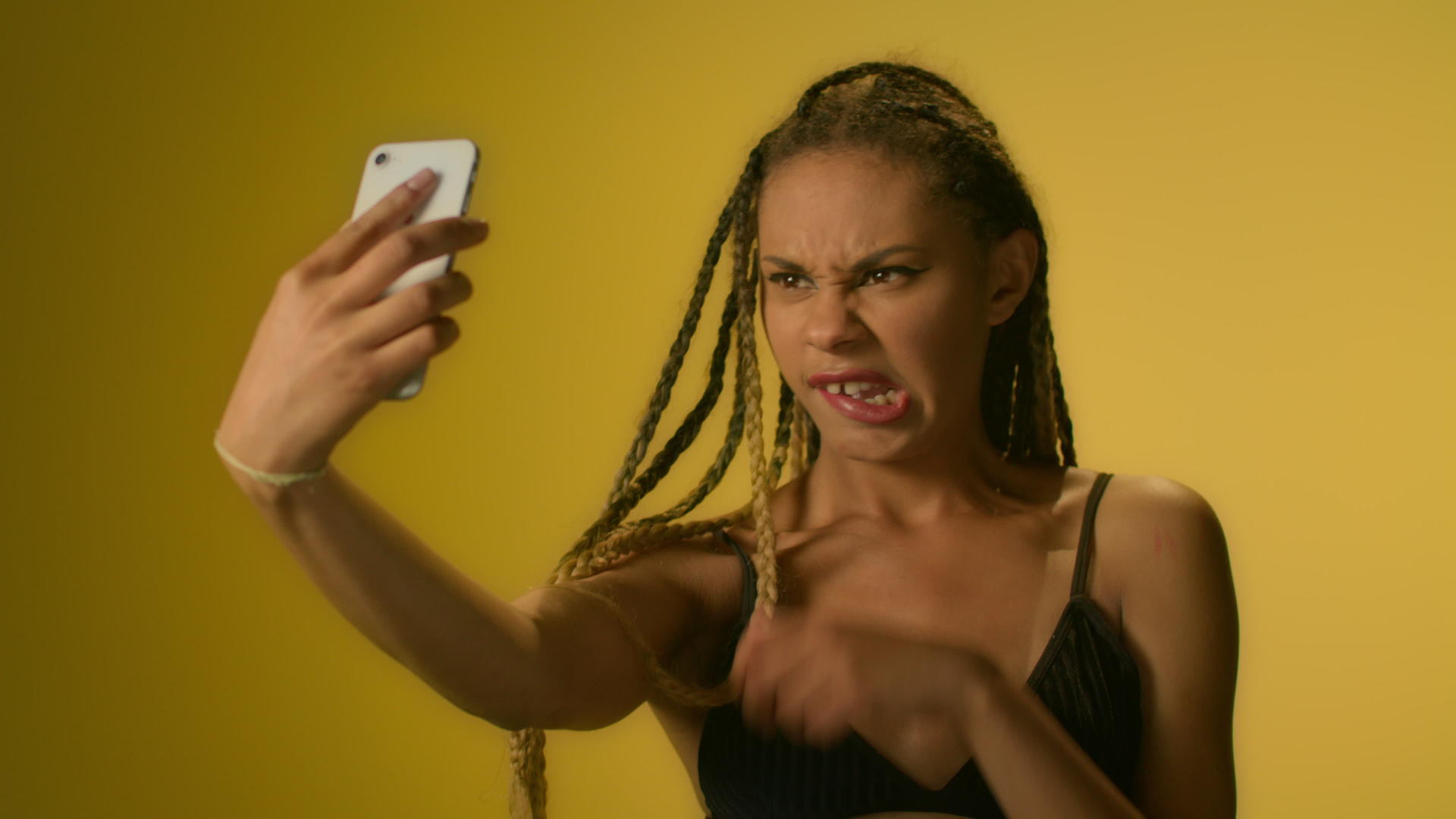 非裔美国女性在黄色背景下假装自动拍摄没有智能手机视频的预览图