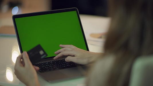 女性在膝盖上用绿色屏幕计算机输入信用卡数据视频的预览图