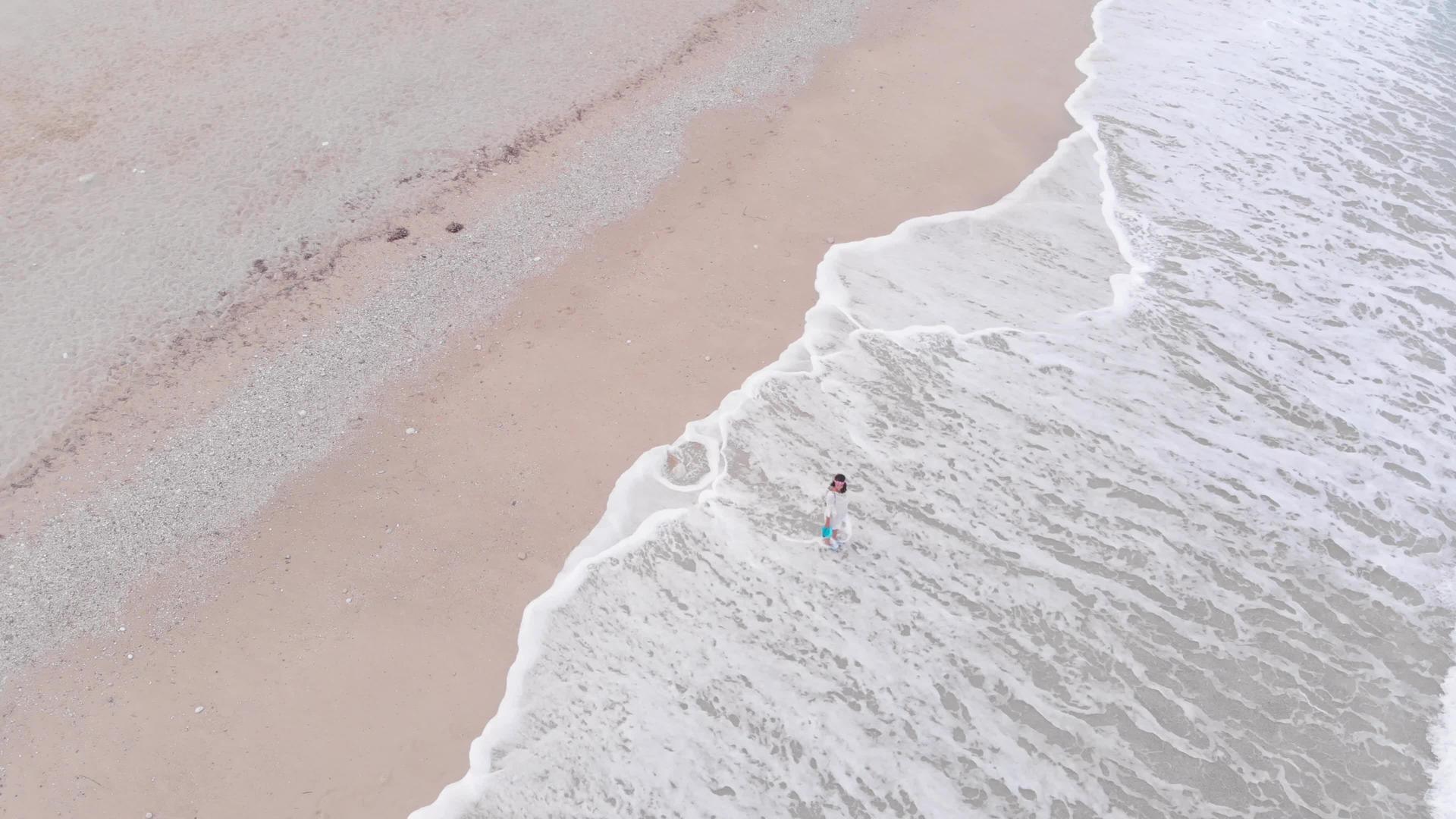 美丽的女人站在海滩上的海浪中视频的预览图
