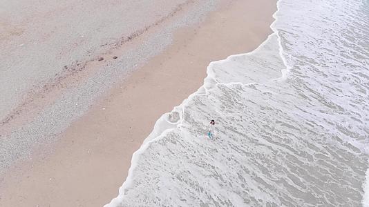 美丽的女人站在海滩上的海浪中视频的预览图