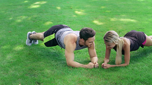 夏季公园草坪上的男女运动员一起参加木板练习视频的预览图