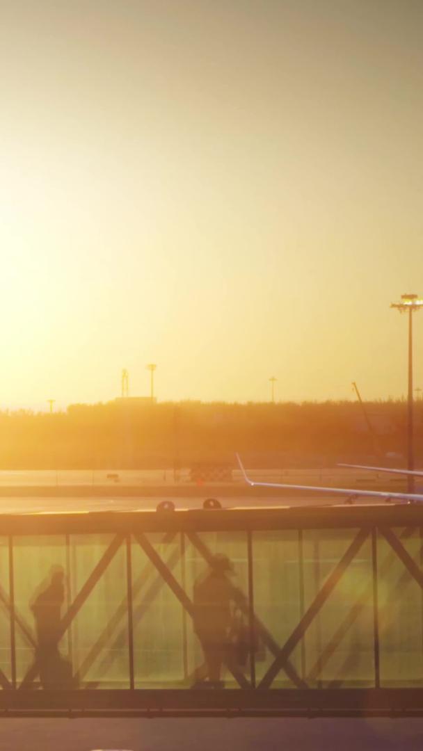 黄昏时分机场廊桥下飞机推着行李箱的乘客视频的预览图
