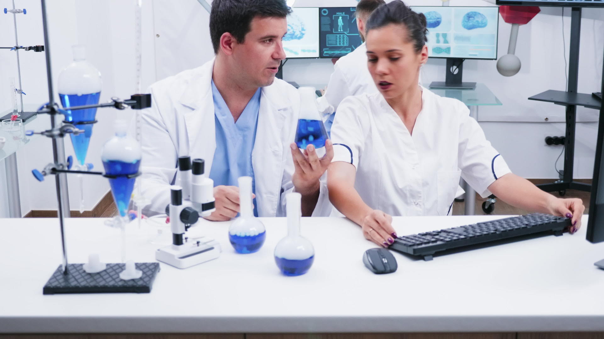 一位身穿白大褂的年轻女科学家和她的助手在现代研究实验室工作视频的预览图