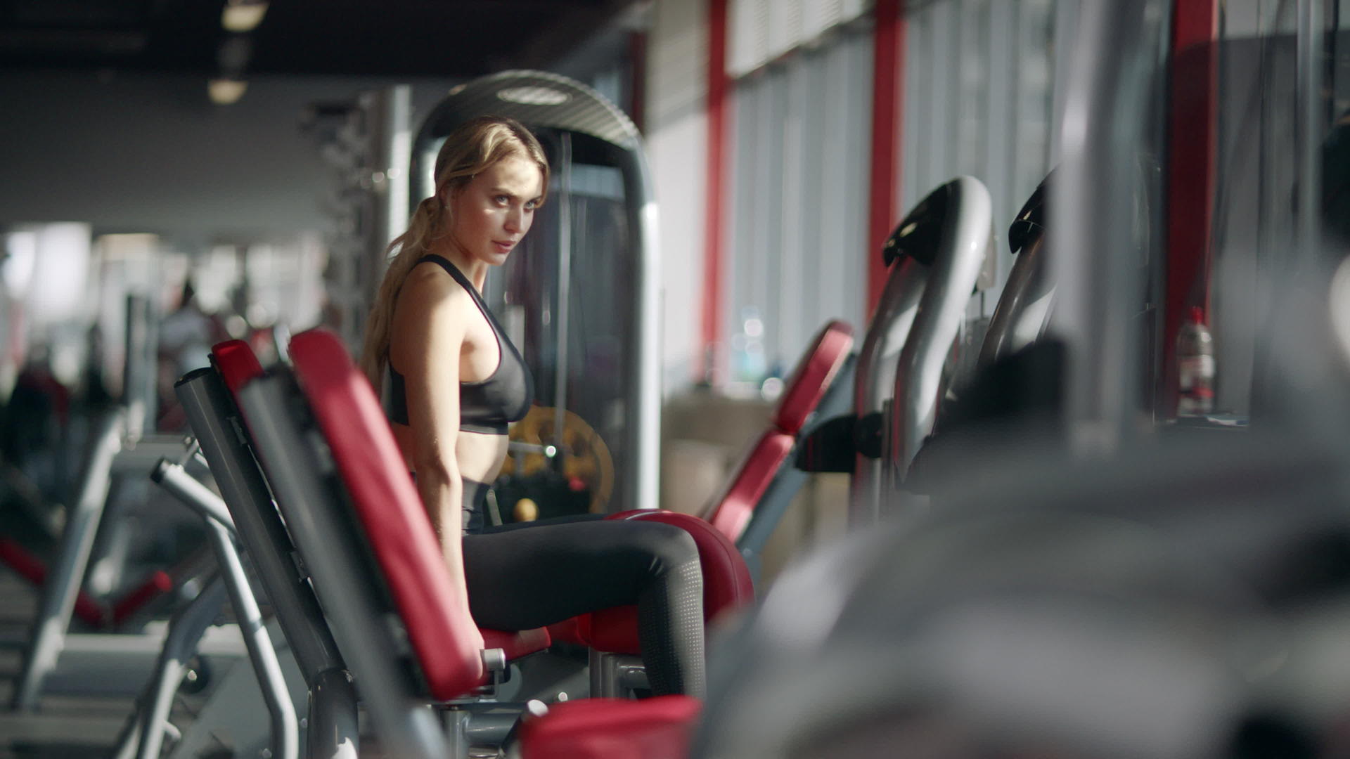 在健身俱乐部运动模拟器上做健身运动的漂亮女人视频的预览图