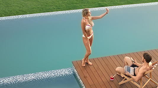 游泳池边的金发女人采用移动自拍视频的预览图