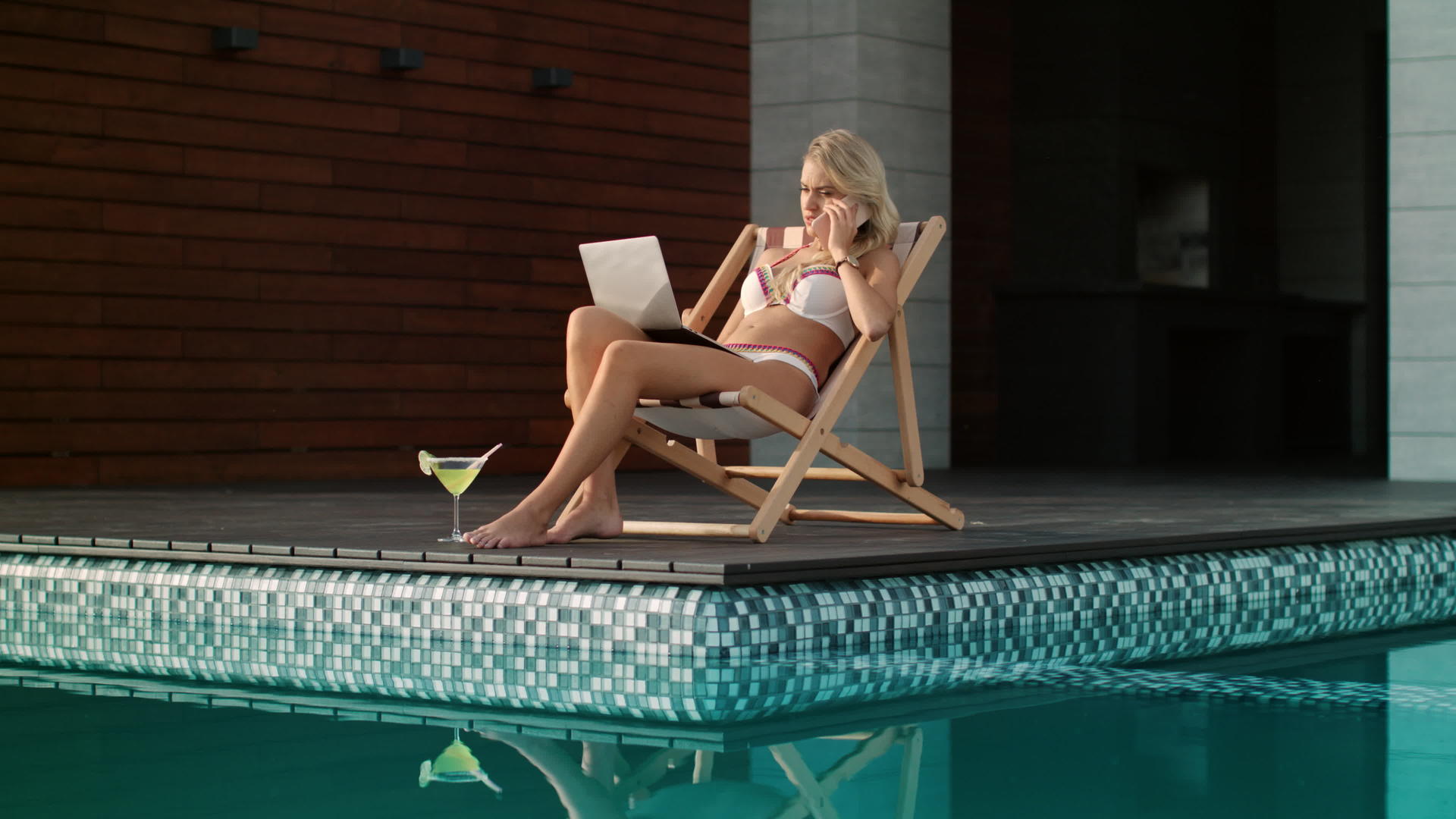 商业女性在游泳池边从事笔记本电脑工作视频的预览图
