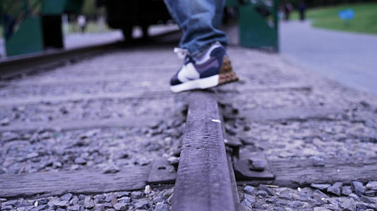 4k慢镜头升格拍摄4k素材火车铁轨上行走的少年脚步特写视频的预览图