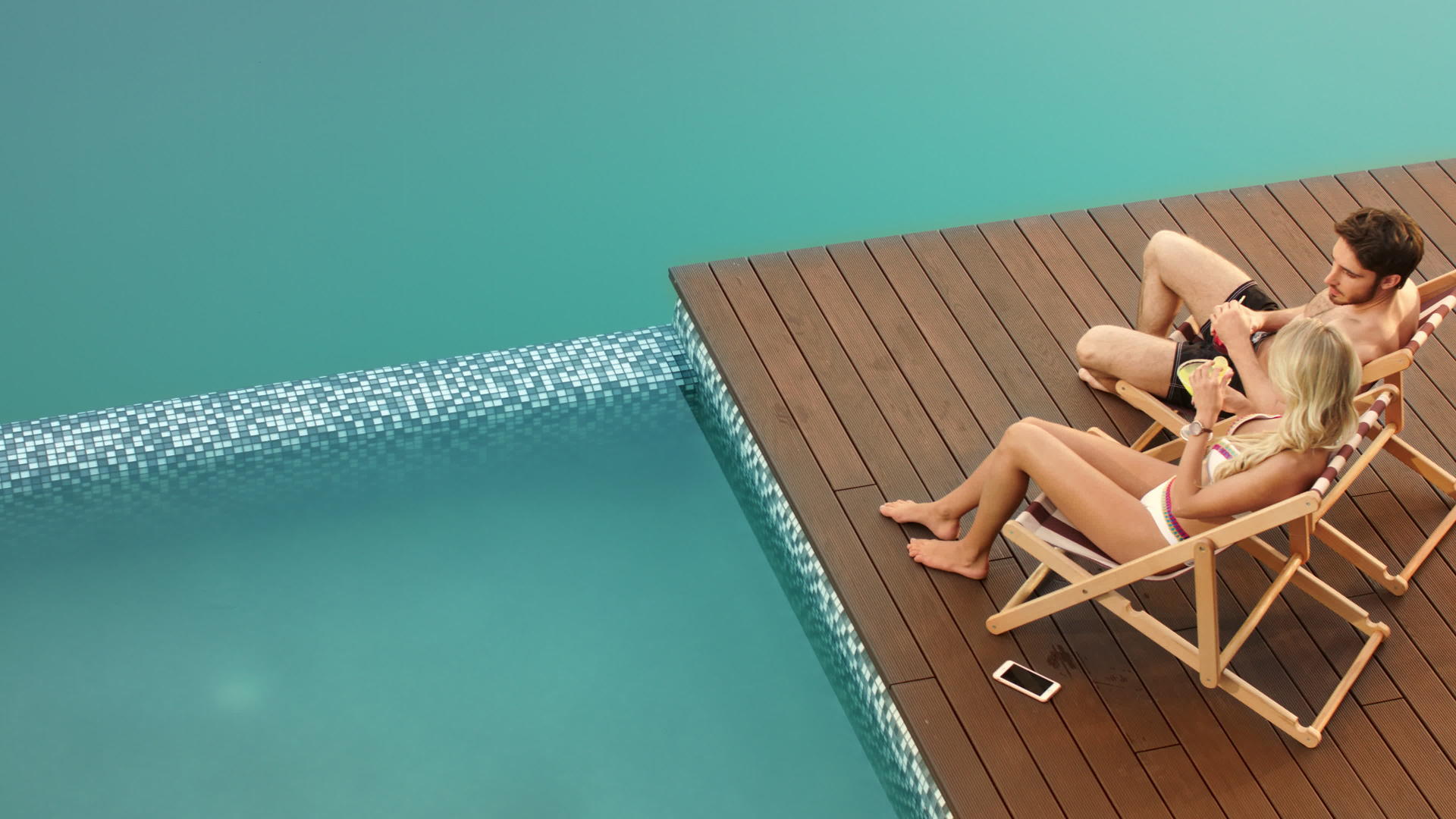 游泳池靠近豪华住宅的游泳池一对欢快的情侣喝着鸡尾酒视频的预览图