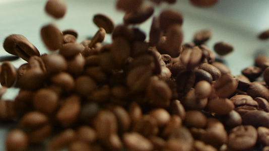 关闭咖啡种子慢慢地扔在金属锅上视频的预览图