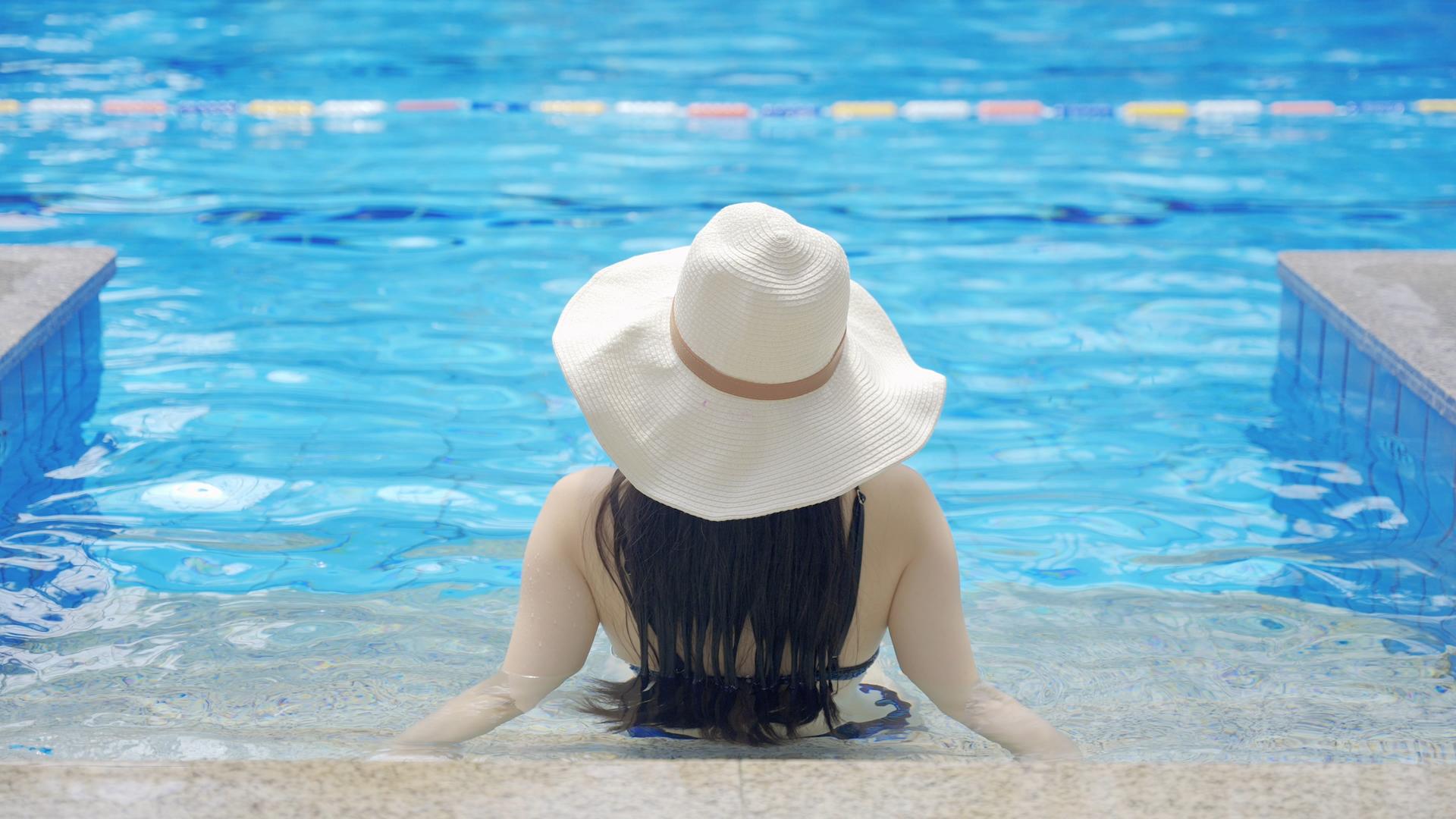 4k游泳池边浸泡水中草帽女性背影视频的预览图